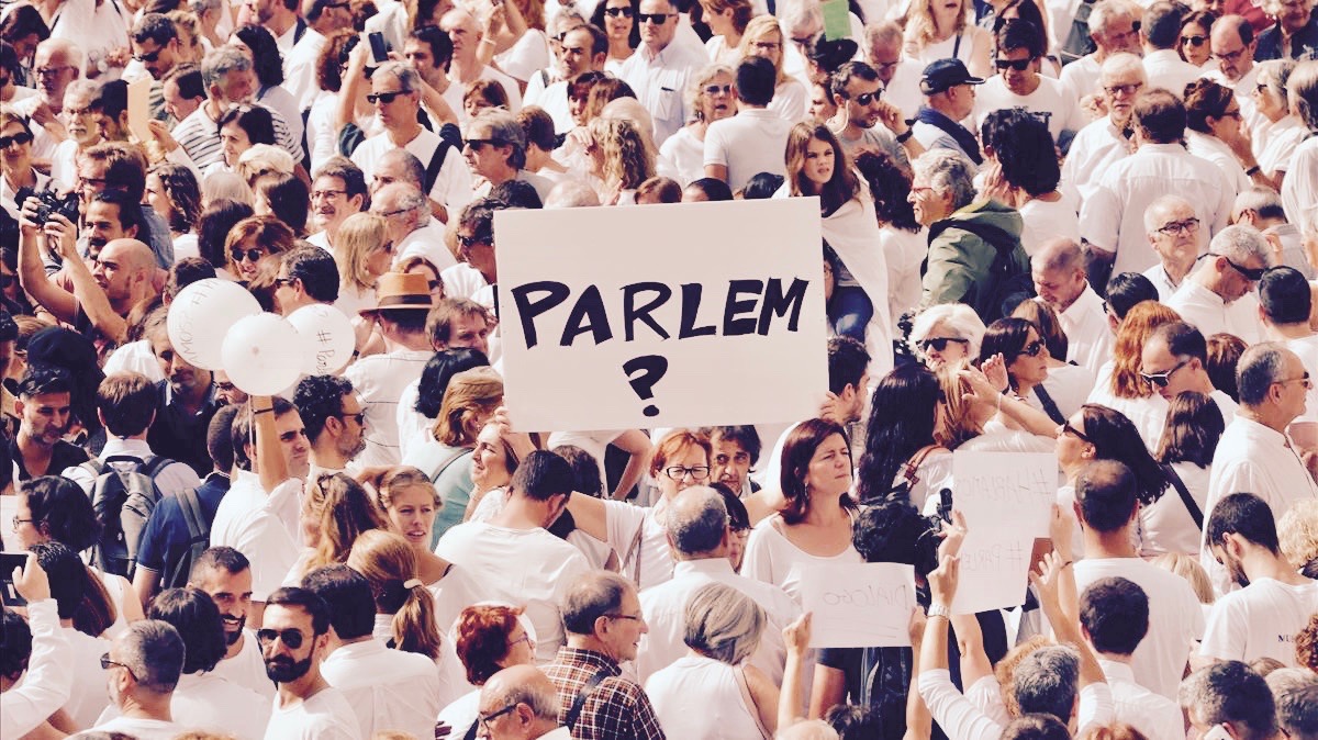 A woman holds up a sign that redads  shall we talk   in Catalan during a demonstration in a square in Barcelona