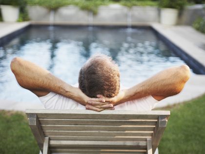 Man sitting with hands behind head admiring swimming pool