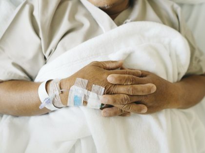 Close up iv tube on hand of Asian senior patient sleep on the bed