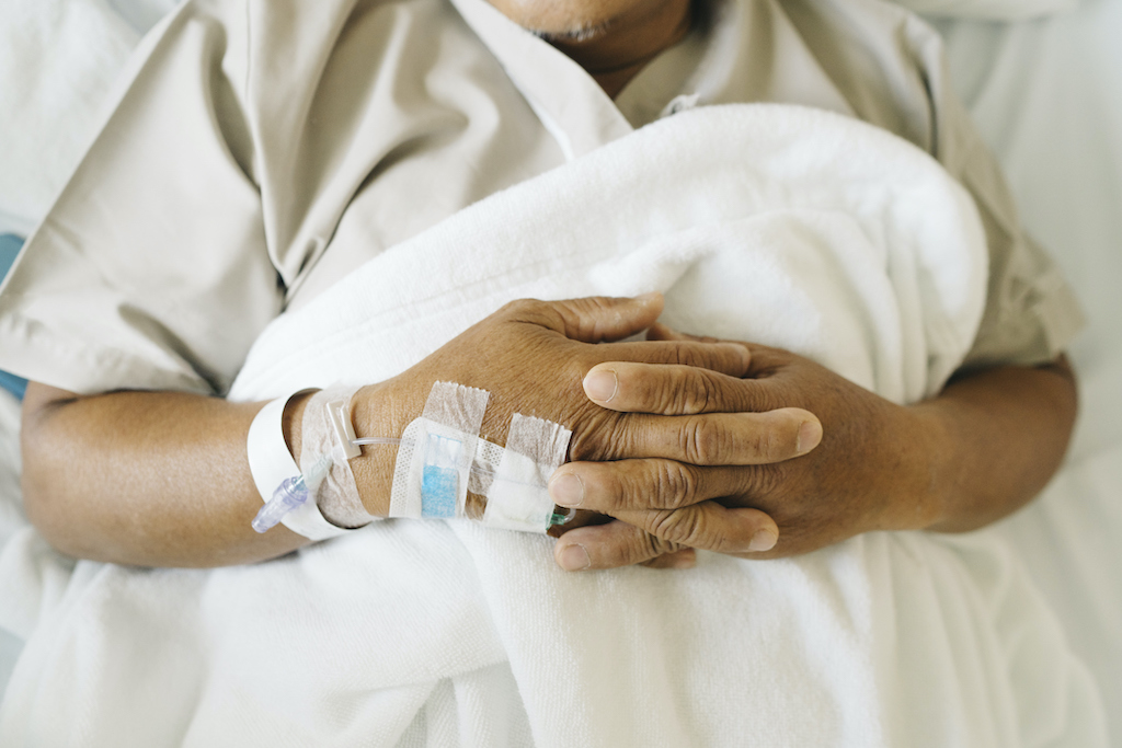 Close up iv tube on hand of Asian senior patient sleep on the bed