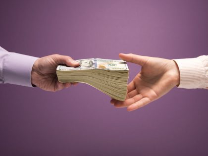 Man and woman's hands handing pile of cash