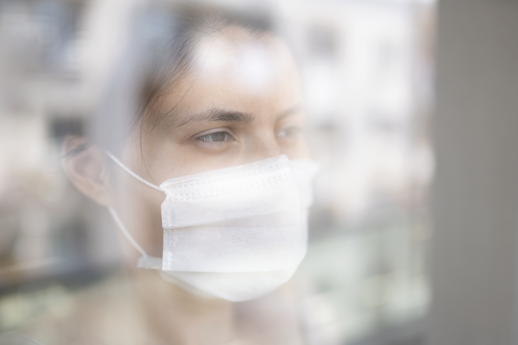 Young woman in quarantine looking through the window
