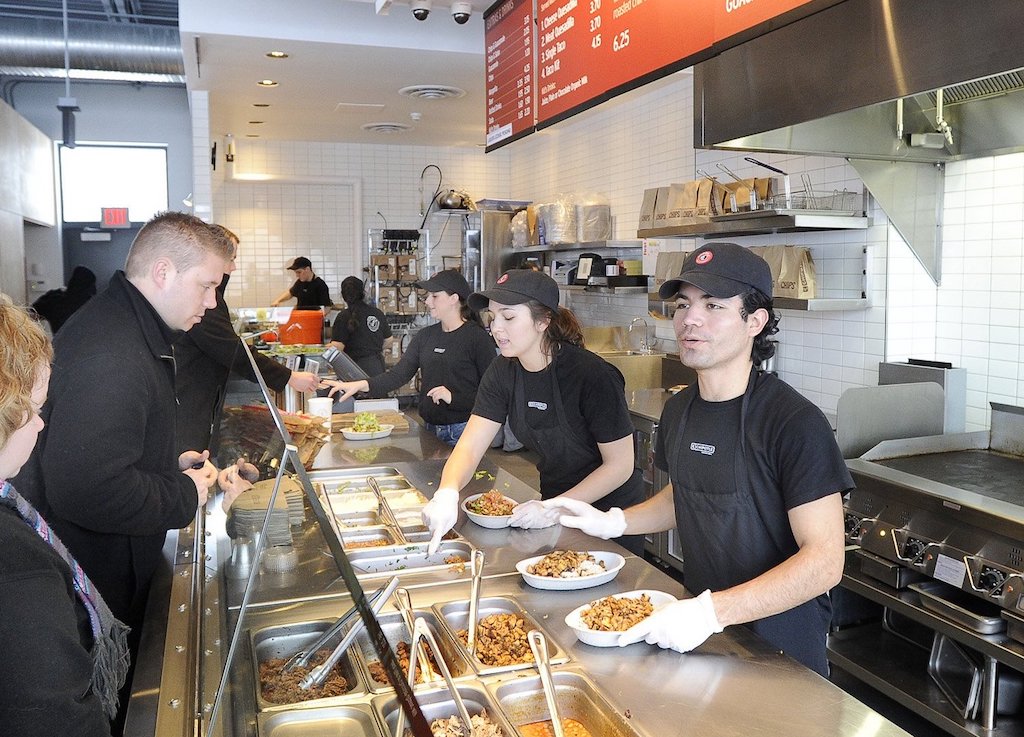 Danny Leon (on right) and Julia Calder (center) serve customers at Chipotle restaurant in South Por