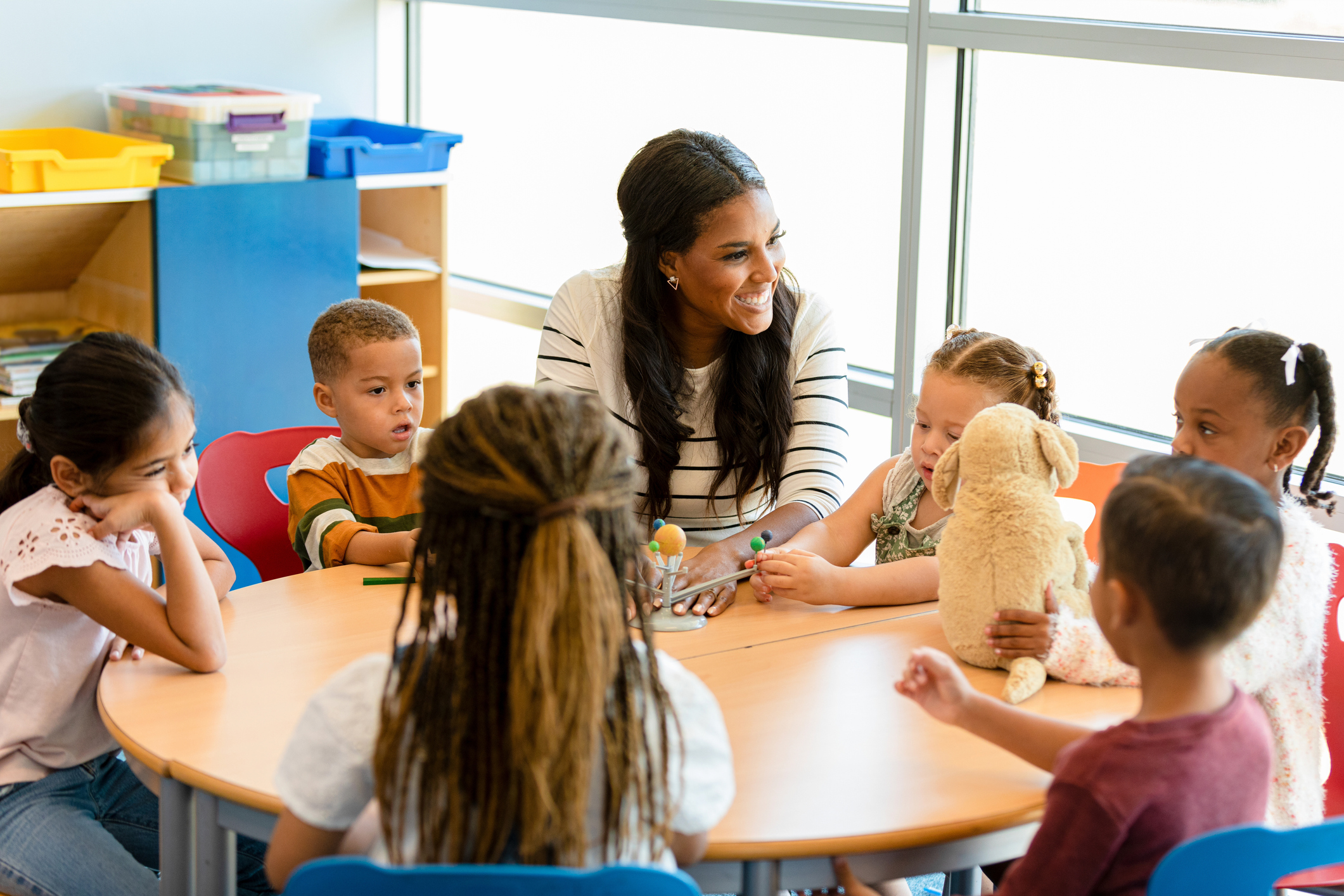 Smiling teacher teaches children about the solar system