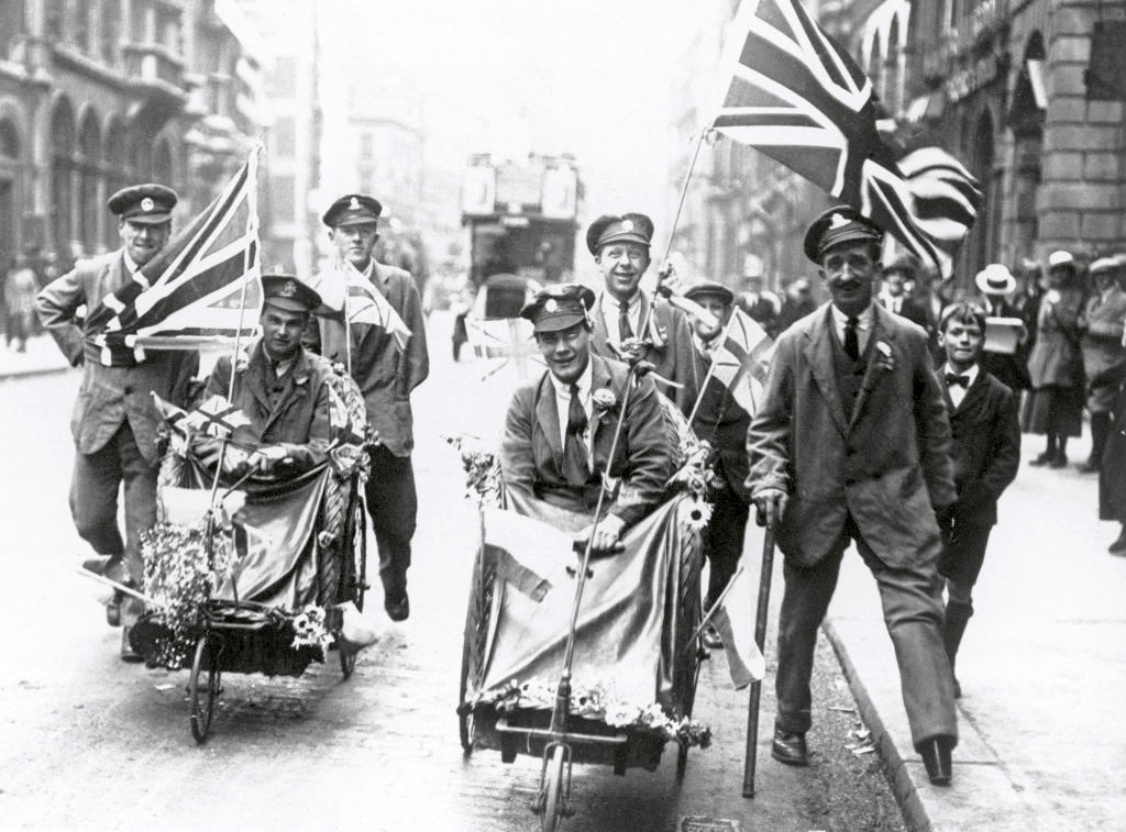 Wounded soldiers in wheelchairs carrying the Union Jack flag