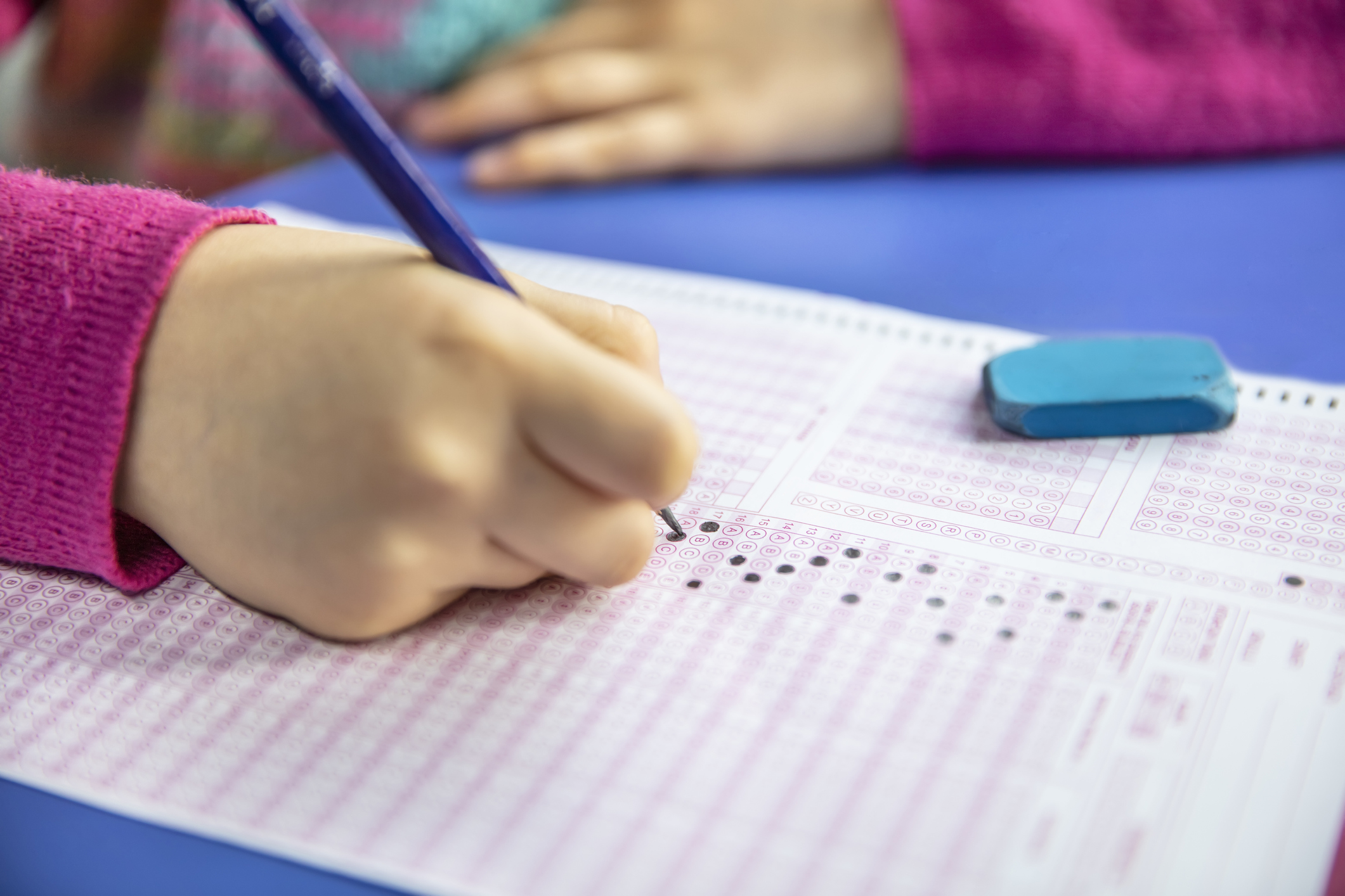 hand student testing in exercise and taking fill in exam carbon paper computer sheet with pencil at school test room, education concept