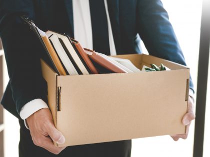 Midsection Of Businessman Carrying Cardboard Box In Office