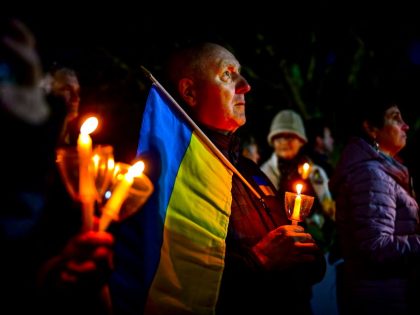 Man holds Ukrainian flag at candelight vigil held for Ukraine on Long Island