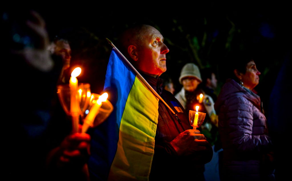 Man holds Ukrainian flag at candelight vigil held for Ukraine on Long Island
