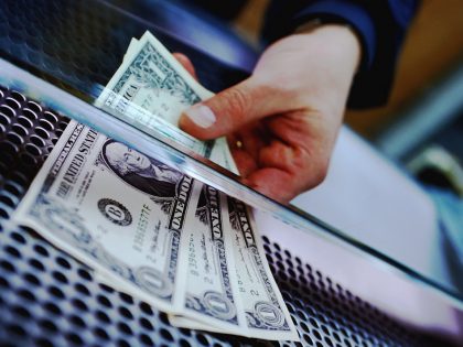 HAND HOLDING THREE AMERICAN DOLLARS