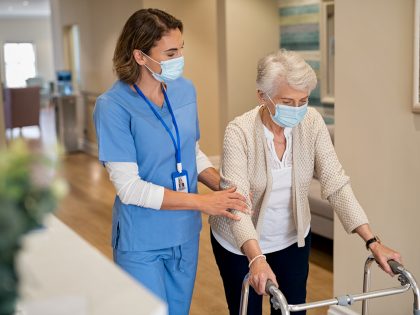 Nurse helping senior woman walk at nursing home