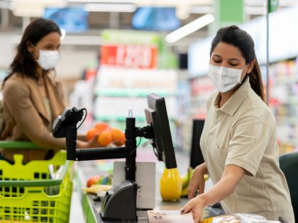 Cashier scanning products at a grocery store wearing a facemask