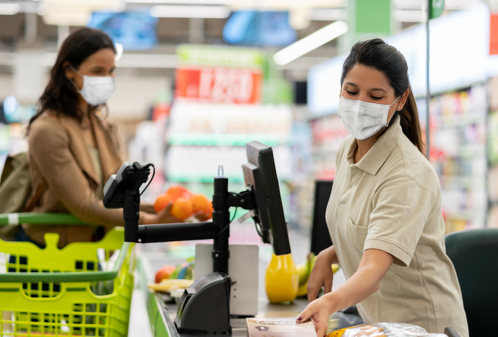 Cashier scanning products at a grocery store wearing a facemask