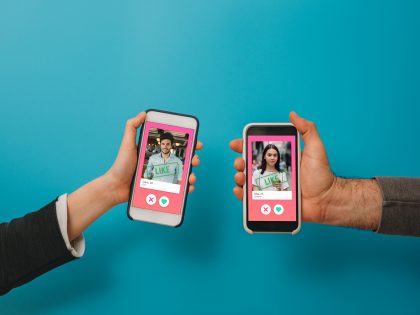 Conceptual image of two hands holding smart phones with an online dating app on the screen