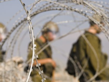 Israeli soldiers behind razor wire in the West Bank