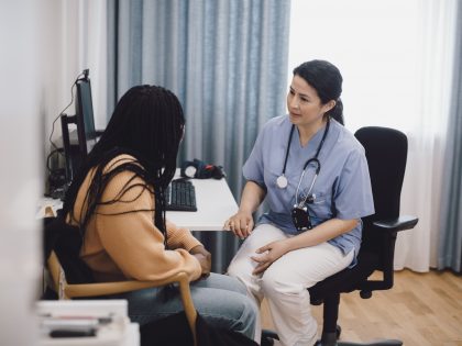 Female doctor giving advice to woman while sitting in medical clinic