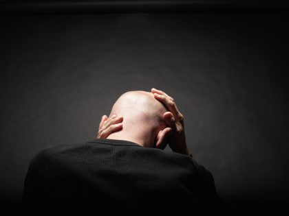 man holding head in hands rear view