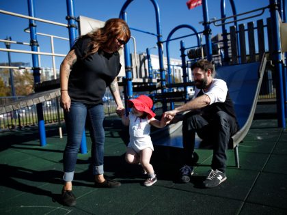 Ann Bruton (center), 21 months, holds the hands of her  mother, Adriel Lively (left) and and father, Jeff Bruton (right),  as she plays on a play structure at a playground at Civic Center Plaza on Wednesday, September 17,  2014 in San Francisco, Calif.
