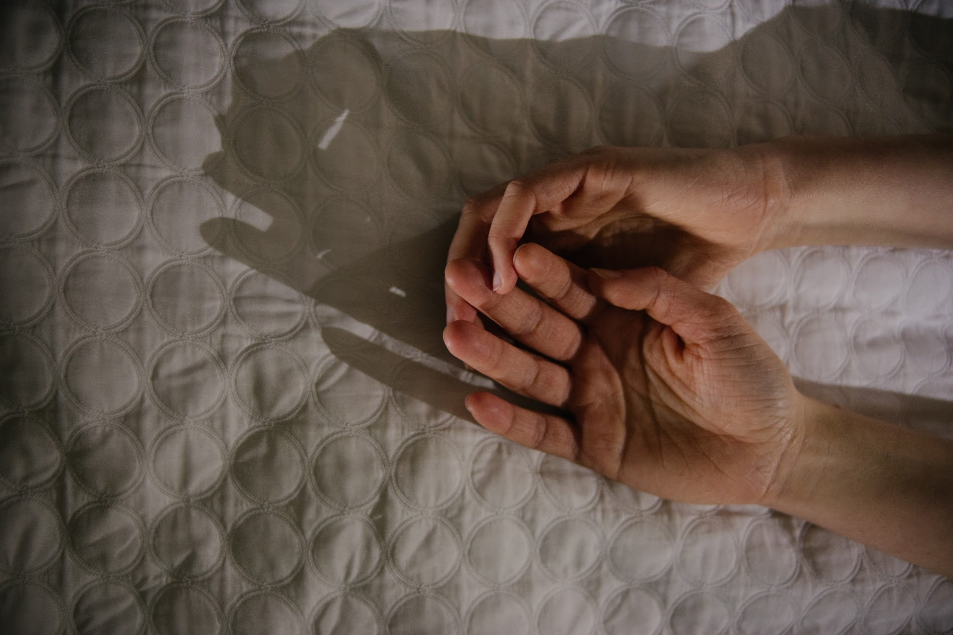 Close-Up Of Hands On Bed