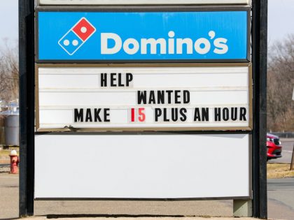 A "help wanted" message is seen on the sign of a Domino's