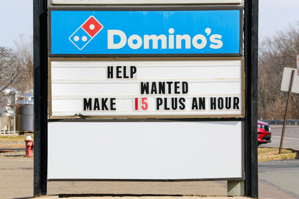 A "help wanted" message is seen on the sign of a Domino's