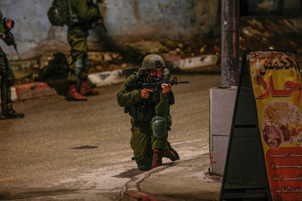 An Israeli soldier seen aiming while other soldiers search