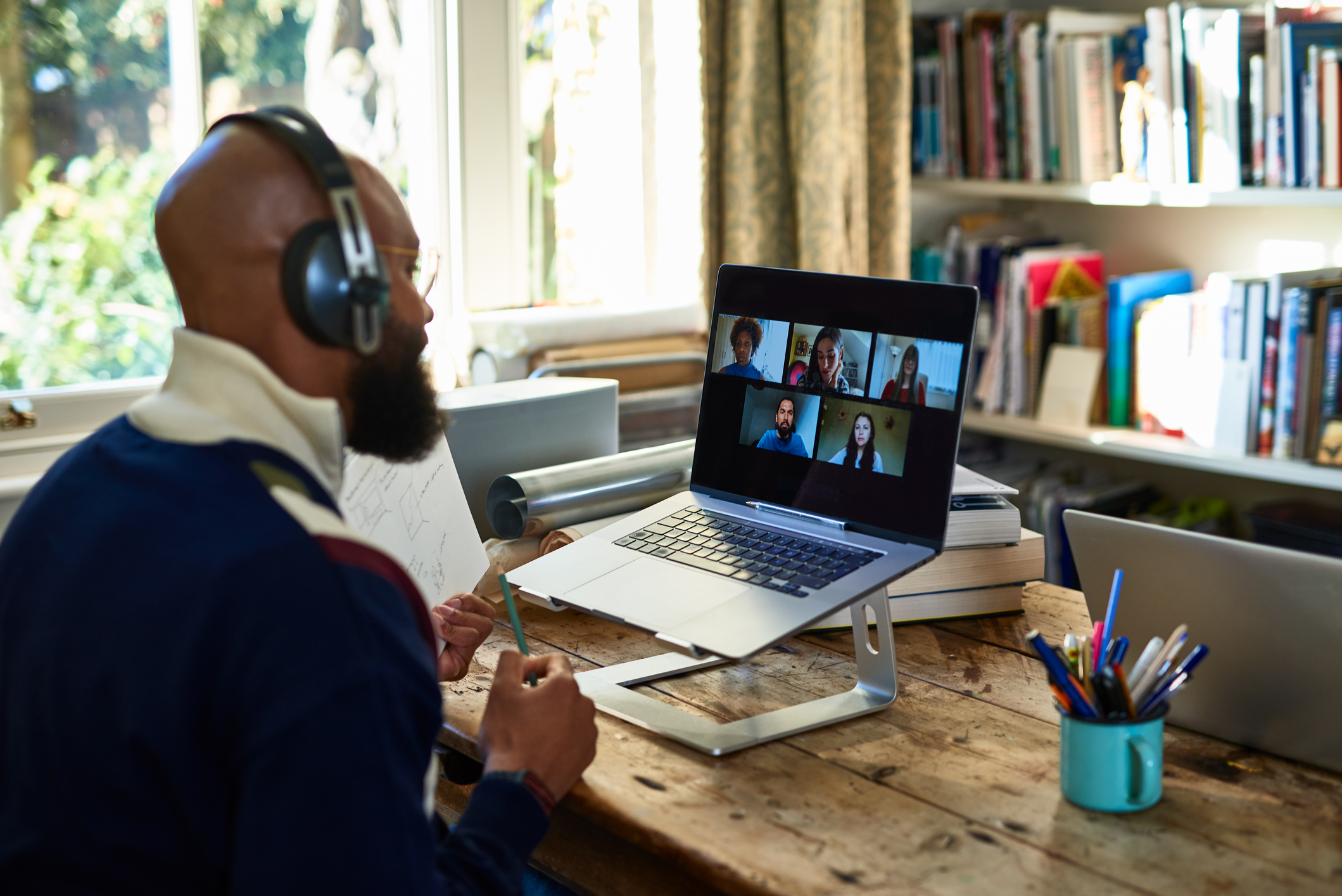 Black entrepreneur wearing headphones on video conference call on laptop in home office