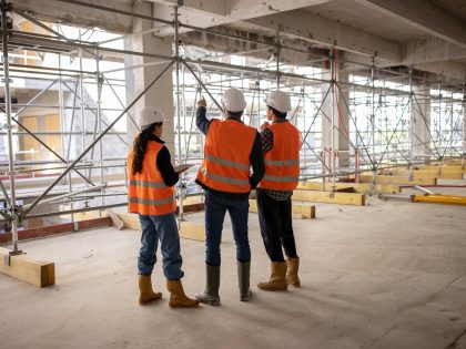 Three workers (architects, engineers) examining building site