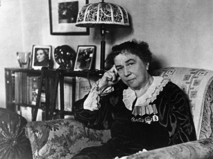 Ambassador alexandra kollontai at her home in moscow, on the bookshelf behind her is a portrait of the minister of republican spain, isabel de palencia, the author of her biography, april 1946.