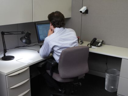 Businessman using laptop in office at desk, rear view