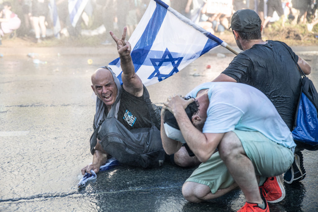 A protester is directly hit by police skunk water cannon