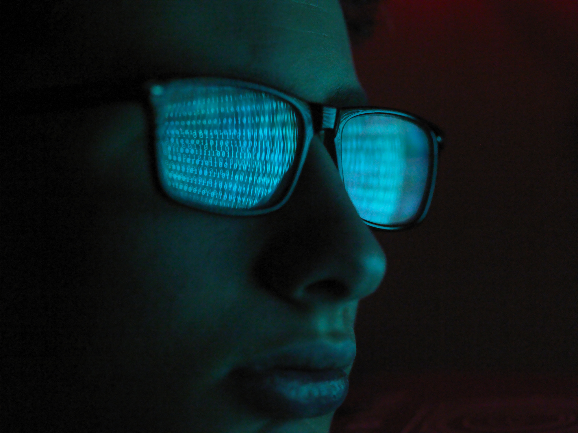 Cyber Crime, reflection in spectacles of virus hacking a computer, close up of face