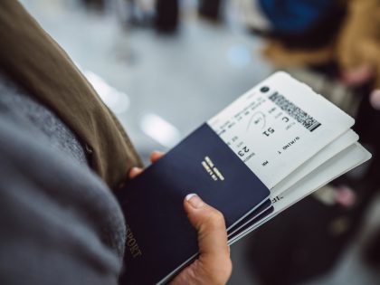 Woman’s hands holding passports &amp;amp; boarding passes of her family while waiting at the check-in counter in the airport