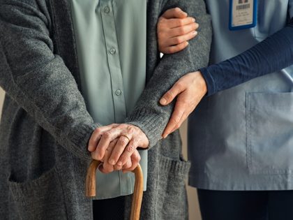 Nurse assisting senior with walking cane