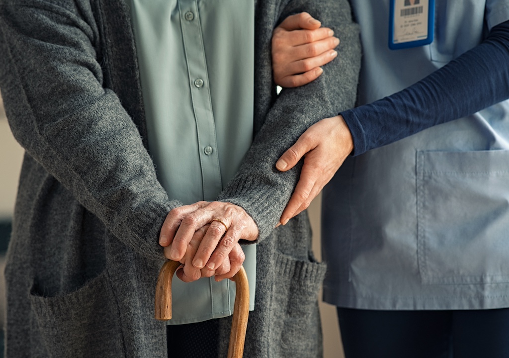 Nurse assisting senior with walking cane