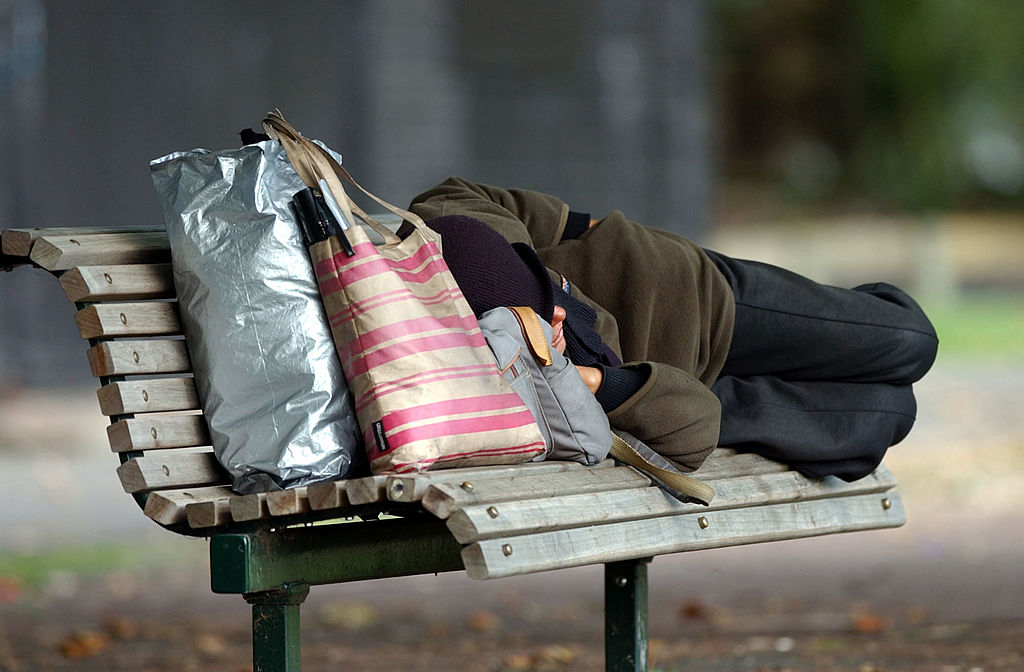 Homeless person sleeping on a park bench at Victor