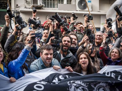 Photojournalists raise their cameras during the protest