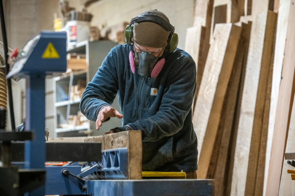 Man cutting pieces of lumber with table saw in wood shop