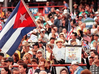 A man waves a Cuban flag and a poster 02 March as