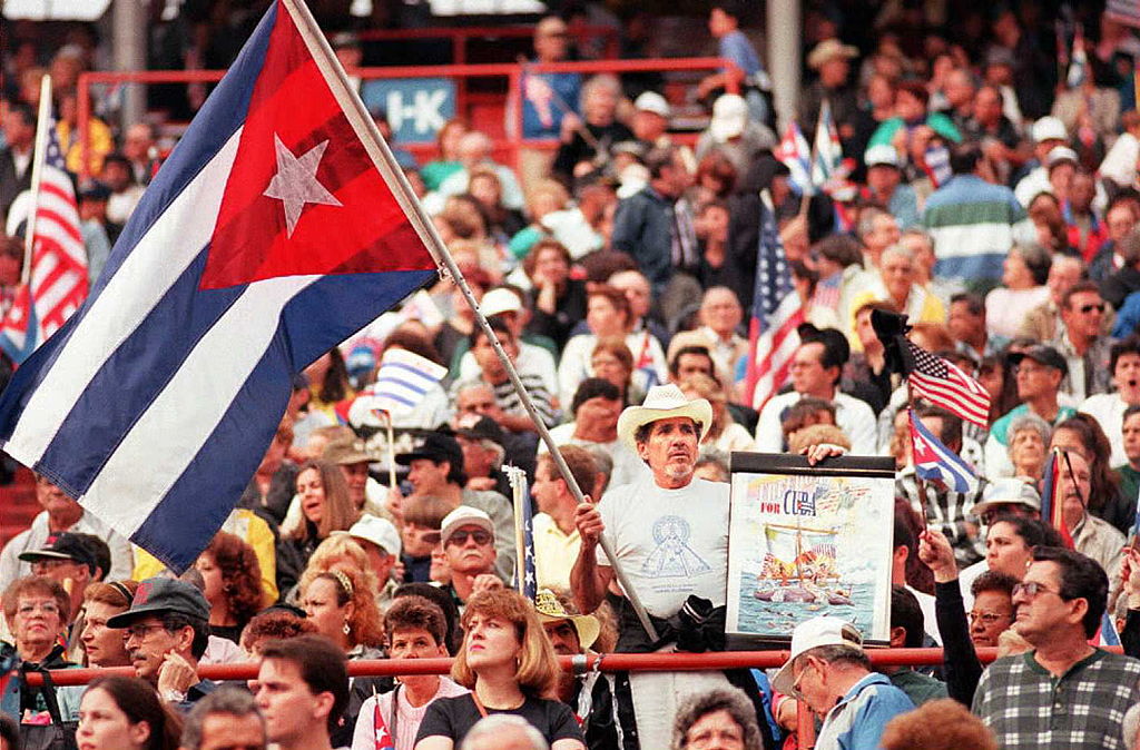 A man waves a Cuban flag and a poster 02 March as