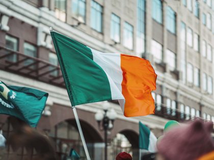 National Flag of Ireland close-up above people crowd, traditional carnival of St. Patrick's Day