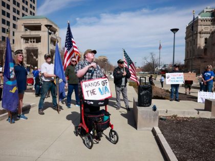 A protester wears a sign reading, "Hands off the VA," as
