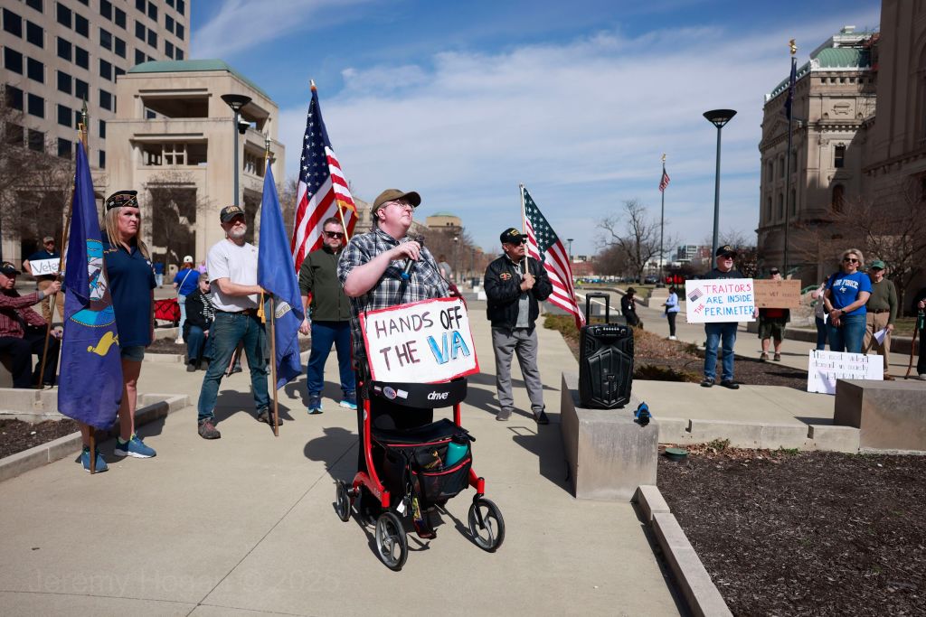 A protester wears a sign reading, "Hands off the VA," as