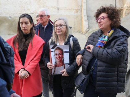 A woman holds a photo of her daughter, a victim who died in