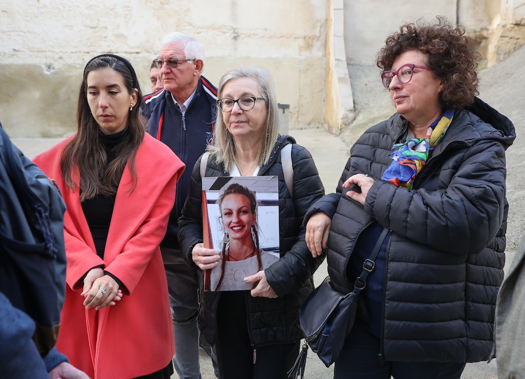 A woman holds a photo of her daughter, a victim who died in