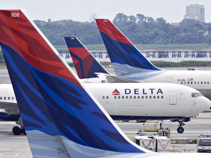 A Delta Air Lines plane taxis toward a gate between other De