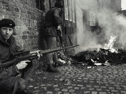 Archival photo: a British soldier provides cover for his fellow soldiers while they check out a burning building in Northern Ireland.