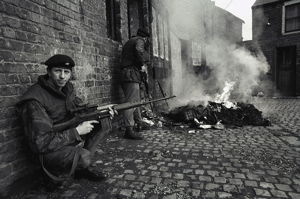 Archival photo: a British soldier provides cover for his fellow soldiers while they check out a burning building in Northern Ireland.