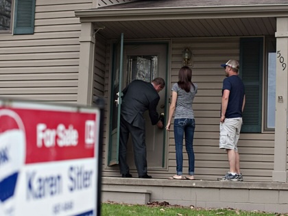 A real estate agent opens the front door of a bank-owned home for potential buyers in Washington, Illinois, on April 21, 2014.