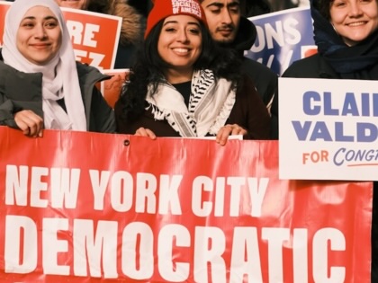 NYC-DSA members carry signs and a large banner bearing the organization's name on a march.